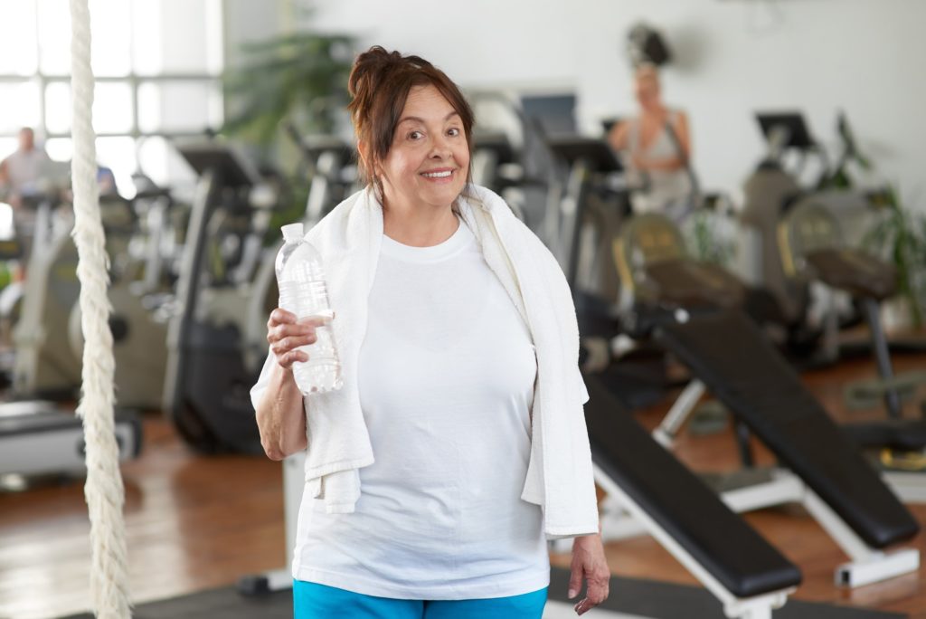 Senior woman holding bottle of water at gym